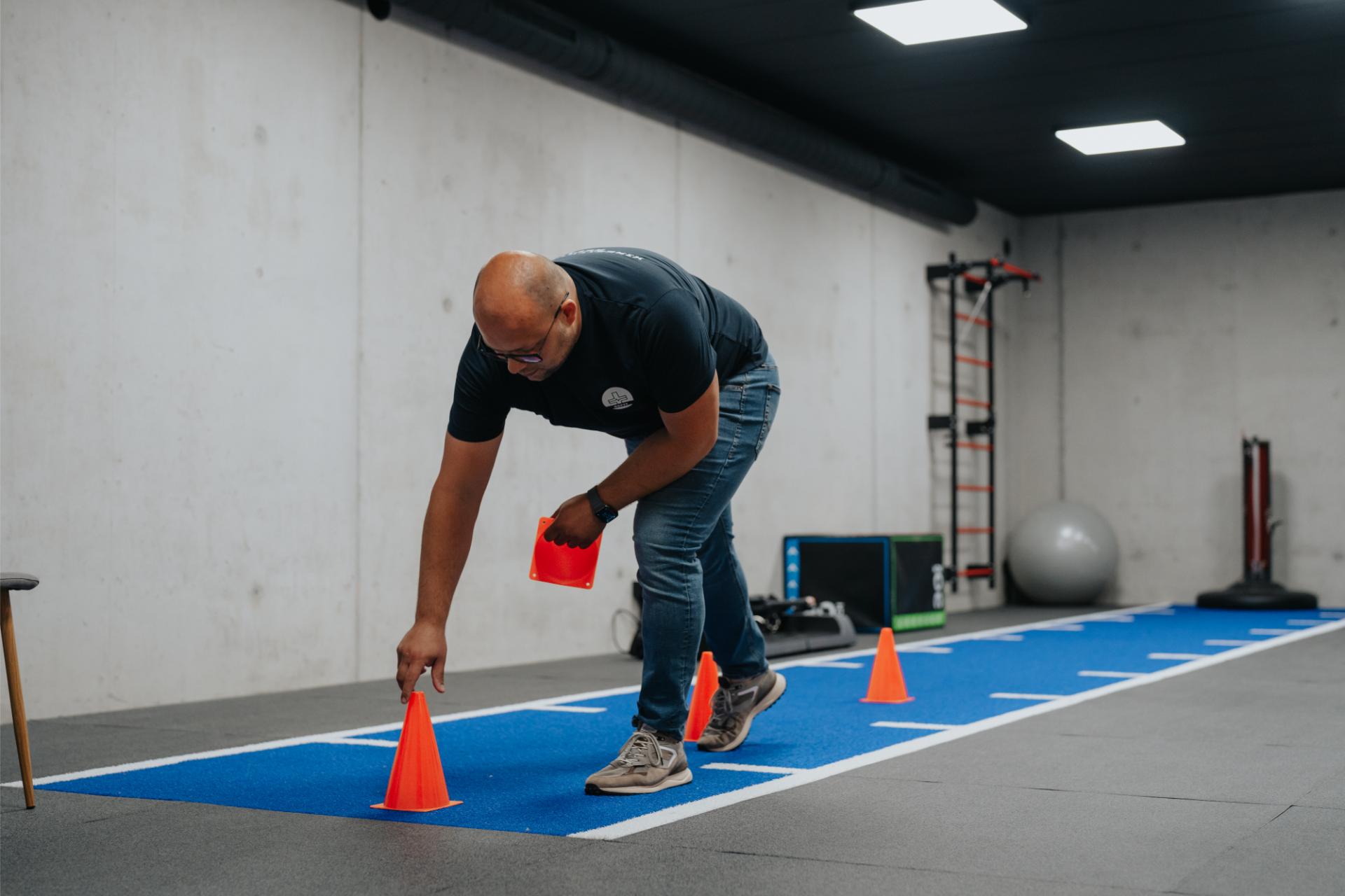 Patiënt doet een oefening met kegels in de oefenzaal van Refit in Pelt
